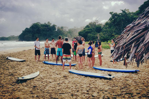 Students on beach with surfboards lying on ground