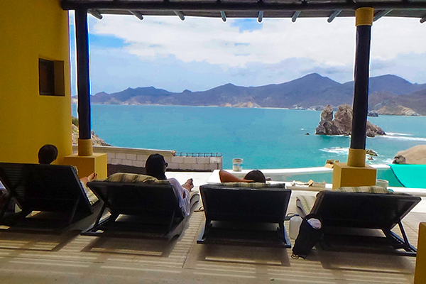 Students lounging in beach chairs on a hotel balcony overlooking the ocean.