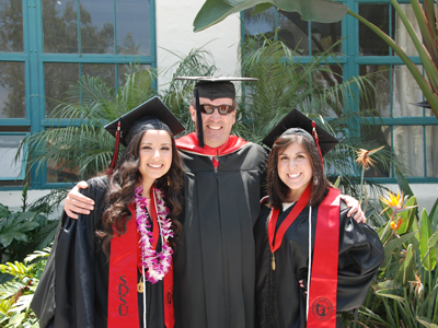 Carl Winston with two students in graduation robes